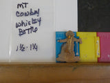 Jaycees Montana Cowboy In Brown Chaps & Yellow Vest Holding Whiskey Bottle .	PIN